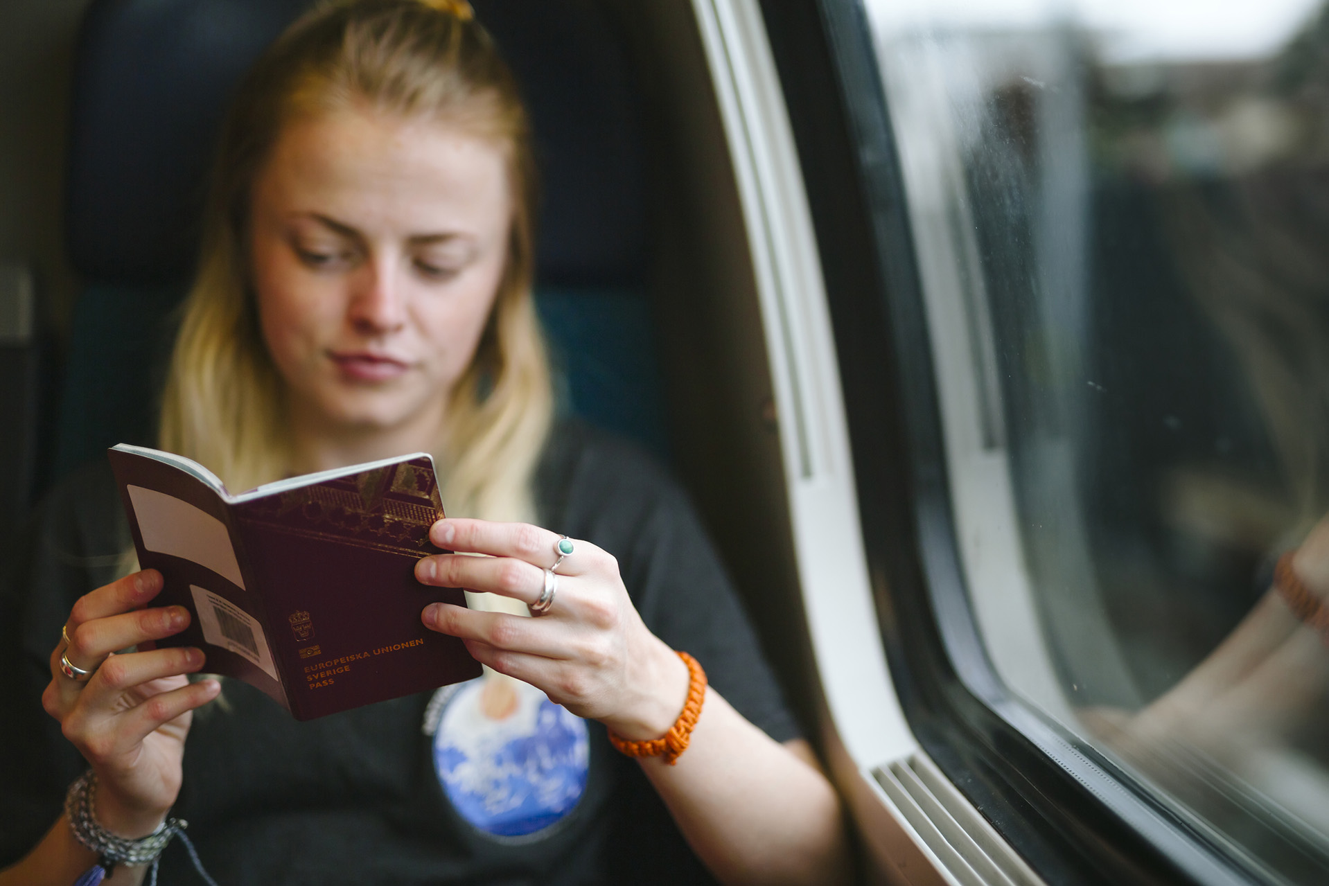 Ung tjej som sitter och tittar i sitt pass på ett tåg.